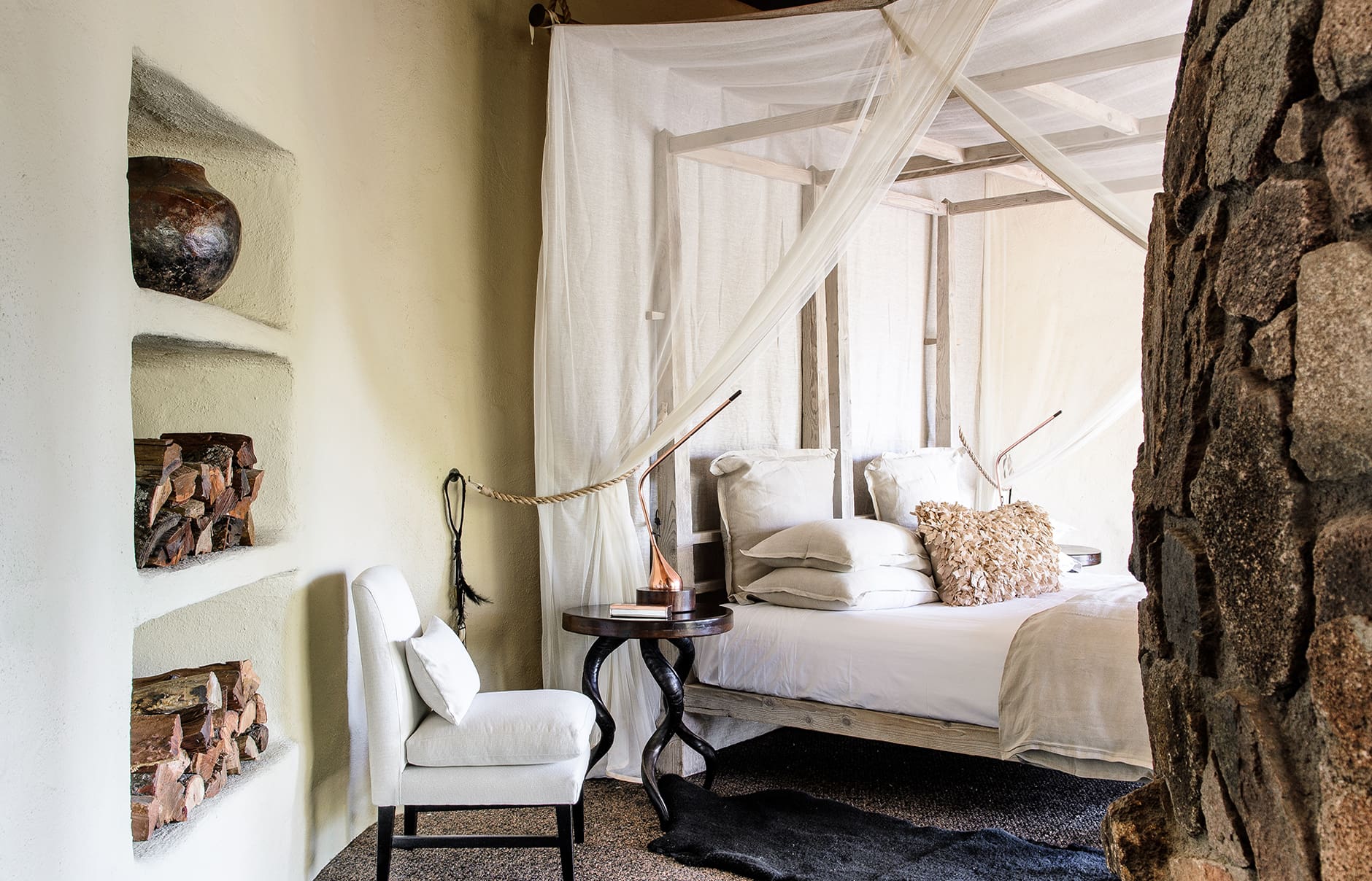 singita-boulders-lodge_river-suite-bedroom-with-white-chair_adriaan-louw